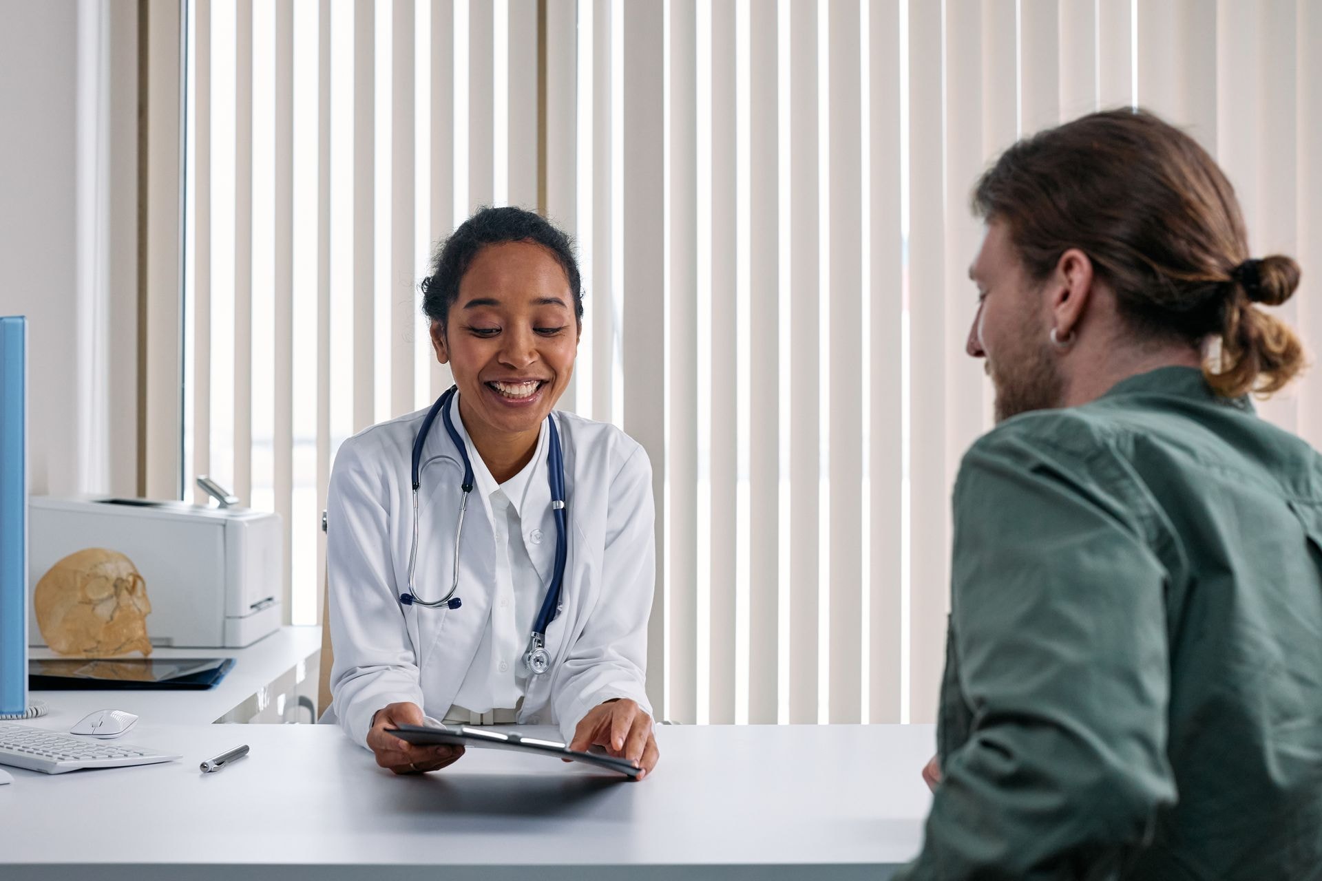 Una médica sonriente con bata blanca muestra un informe a un paciente en su consulta