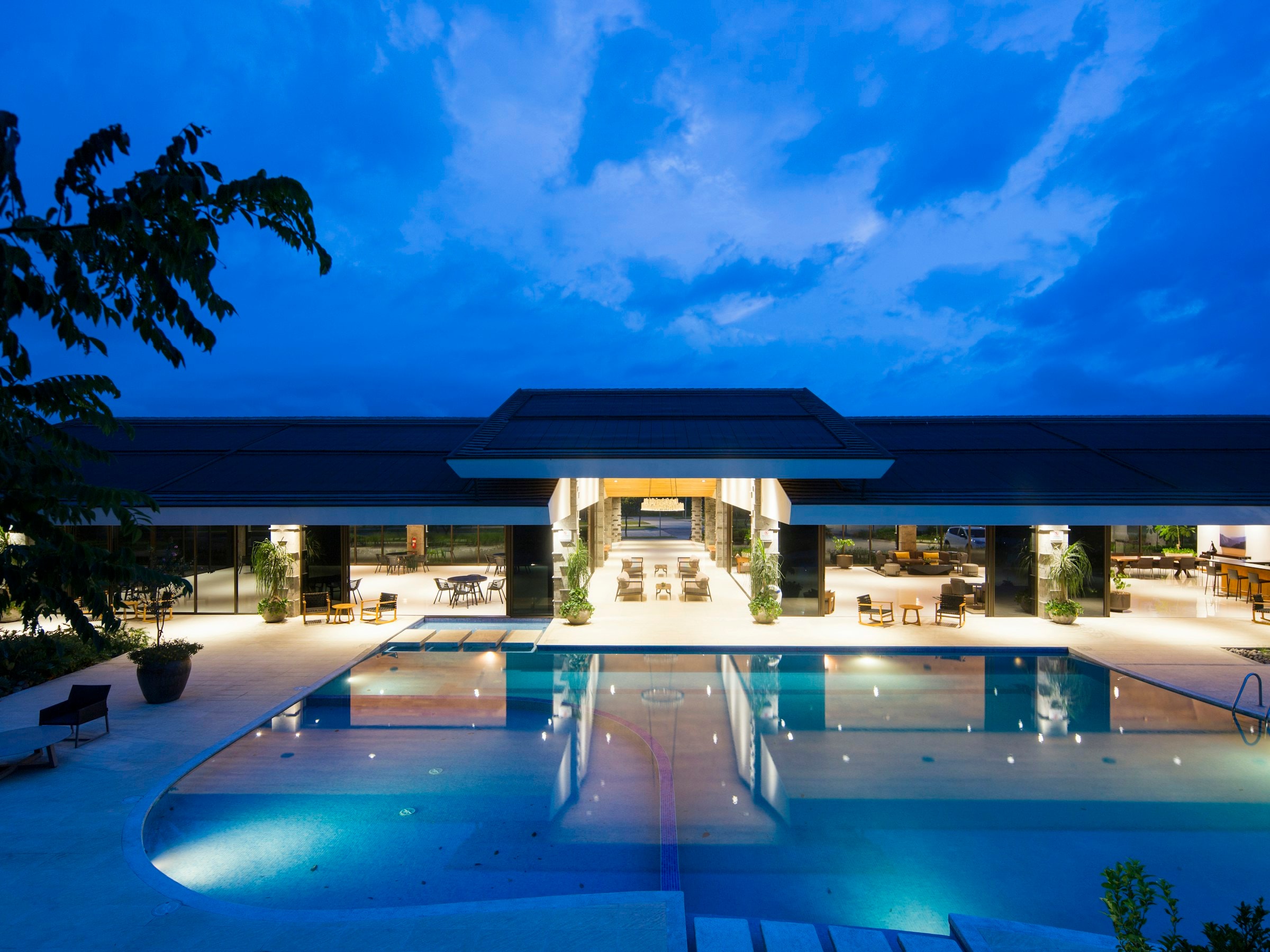 Hotel resort de lujo al anochecer con la piscina iluminada y terrazas abiertas con salones