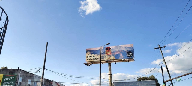Valla publicitaria con un anuncio de bebida en lata sobre un cielo azul en una calle urbana