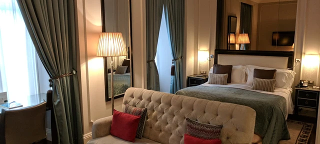 Habitación de hotel elegante con cama, sofá capitoné y lámparas cálidas